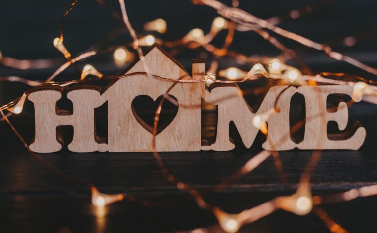 close up of a wooden sign home and fairy lights